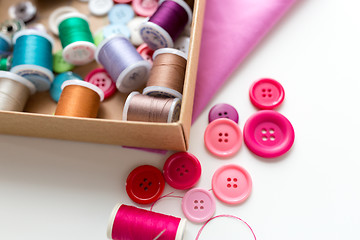 Image showing box with thread spools and sewing buttons on table