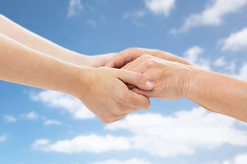 Image showing close up of senior and young woman holding hands