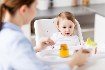 Image showing happy mother feeding baby with puree at home