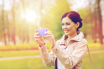 Image showing smiling woman taking picture with smartphone