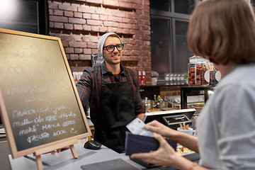 Image showing happy barman and woman paying money at cafe