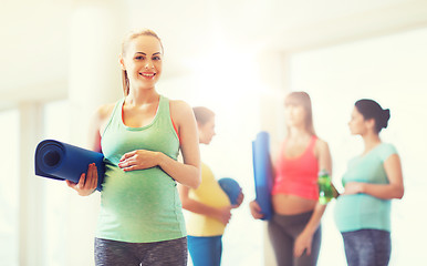 Image showing happy pregnant woman with mat in gym