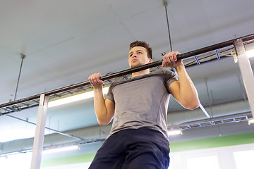 Image showing man exercising on bar and doing pull-ups in gym