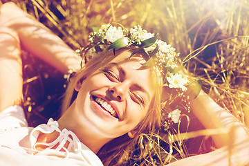 Image showing happy woman in wreath of flowers lying on straw