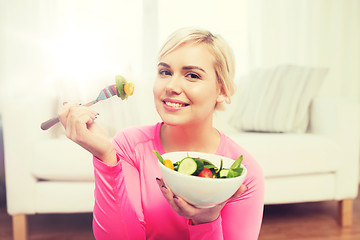 Image showing smiling young woman eating salad at home