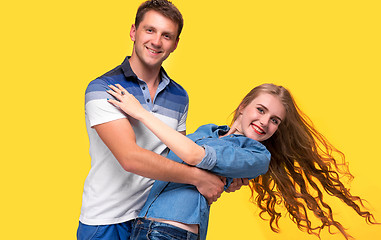 Image showing Portrait of a young couple standing against yellow background