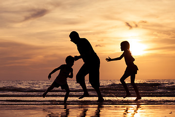 Image showing Father and children playing on the beach at the sunset time.