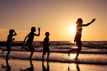 Image showing Mother and children playing on the beach at the sunset time.