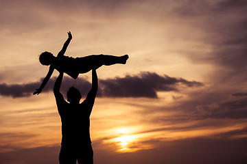 Image showing Father and son playing on the beach at the sunset time.