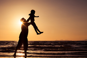 Image showing Father and son playing on the beach at the sunset time.