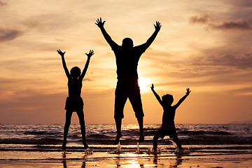 Image showing Father and children playing on the beach at the sunset time.