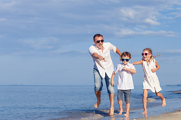 Image showing Father and children playing on the beach at the day time.