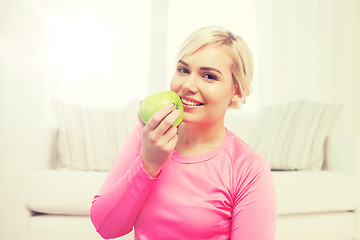 Image showing happy woman eating apple at home