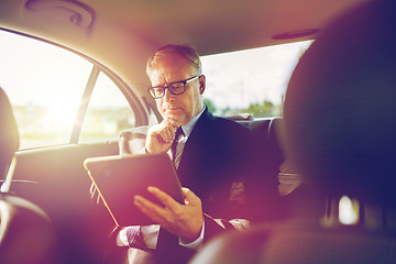 Image showing senior businessman with tablet pc driving in car