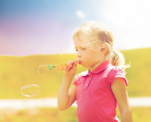 Image showing little girl blowing soap bubbles outdoors