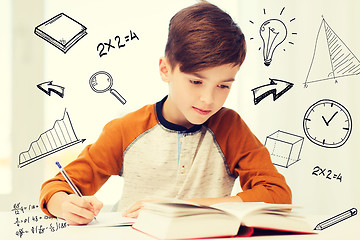 Image showing student boy with book writing to notebook at home