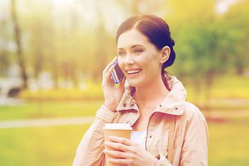 Image showing smiling woman with smartphone and coffee in park