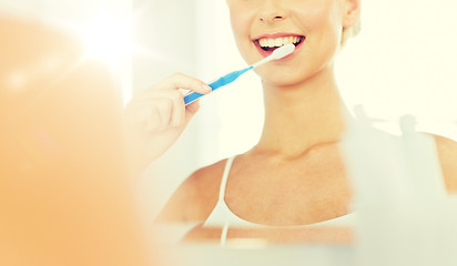 Image showing woman with toothbrush cleaning teeth at bathroom