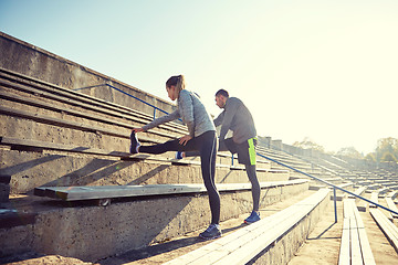 Image showing couple stretching leg on stands of stadium