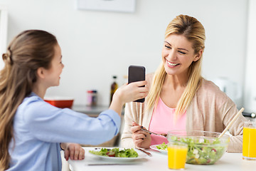 Image showing happy family with smartphone having dinner at home