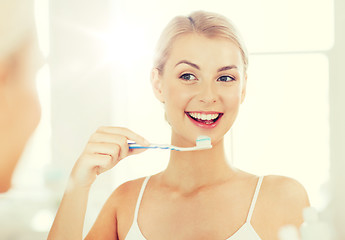 Image showing woman with toothbrush cleaning teeth at bathroom