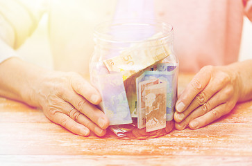 Image showing close up of senior woman with money in glass jar