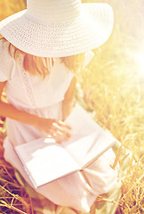 Image showing close up of woman reading book on cereal field