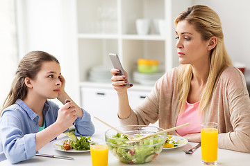 Image showing sad girl looking at her mother with smartphone