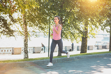 Image showing Pretty sporty woman jogging at park in sunrise light