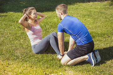 Image showing Fit fitness woman and man doing stretching exercises outdoors at park