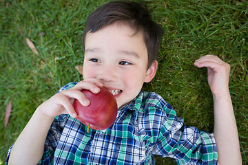 Image showing Mixed Race Chinese and Caucasian Young Boy With Apple Relaxing O