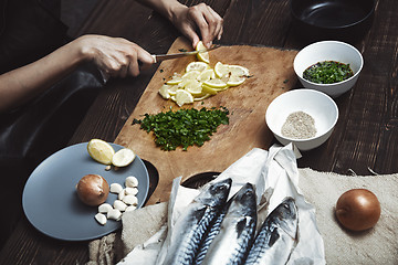 Image showing Woman cutting lemon for fish stuffing