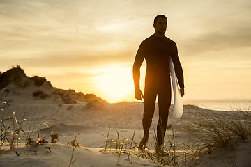 Image showing A surfer with his surfboard 