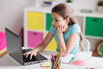Image showing bored girl with laptop and notebook at home