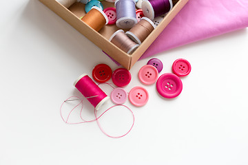 Image showing box with thread spools and sewing buttons on table