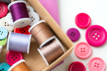 Image showing box with thread spools and sewing buttons on table