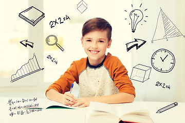 Image showing smiling student boy writing to notebook at home