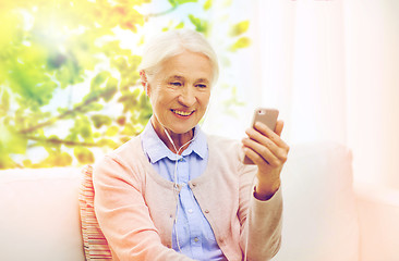 Image showing senior woman with smartphone and earphones at home