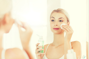 Image showing young woman with lotion washing face at bathroom