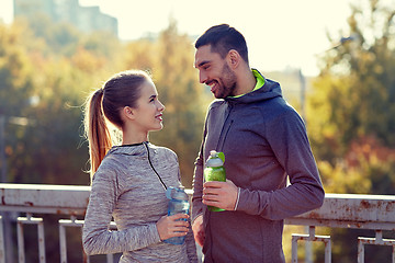 Image showing smiling couple with bottles of water outdoors