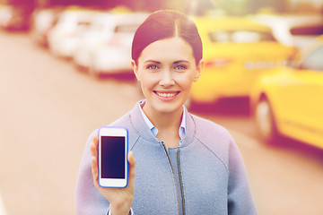 Image showing smiling woman showing smartphone over taxi in city