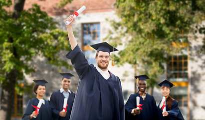 Image showing happy students in mortar boards with diplomas