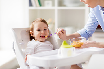 Image showing happy mother feeding baby with puree at home