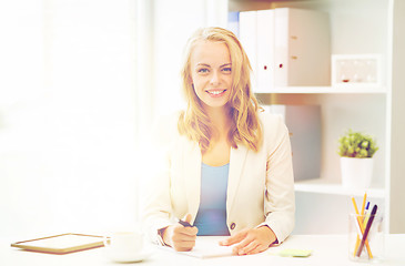 Image showing businesswoman writing to notebook at office