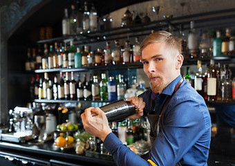 Image showing barman with shaker preparing cocktail at bar