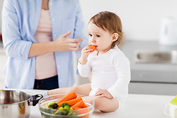 Image showing happy mother and baby eating at home kitchen