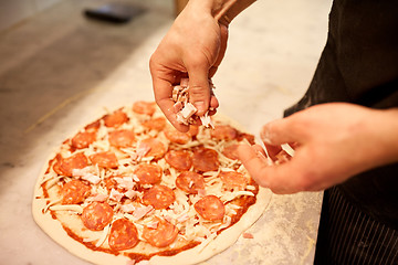 Image showing cook hands adding ham to salami pizza at pizzeria