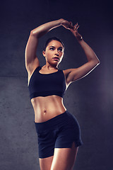 Image showing young woman posing and showing muscles in gym