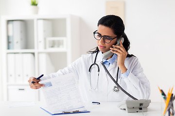 Image showing doctor with clipboard calling on phone at hospital