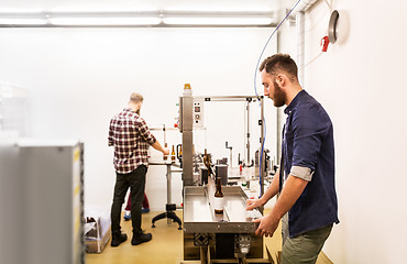 Image showing men with bottles on conveyor at craft beer brewery